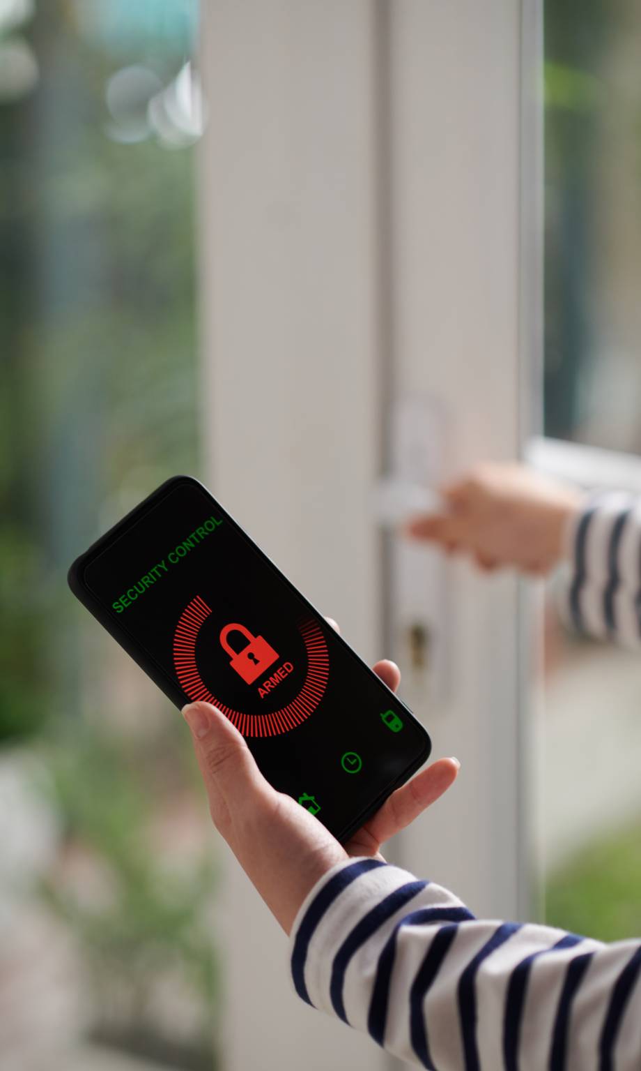 Hands of young woman using security control application on smartphone to set alarm